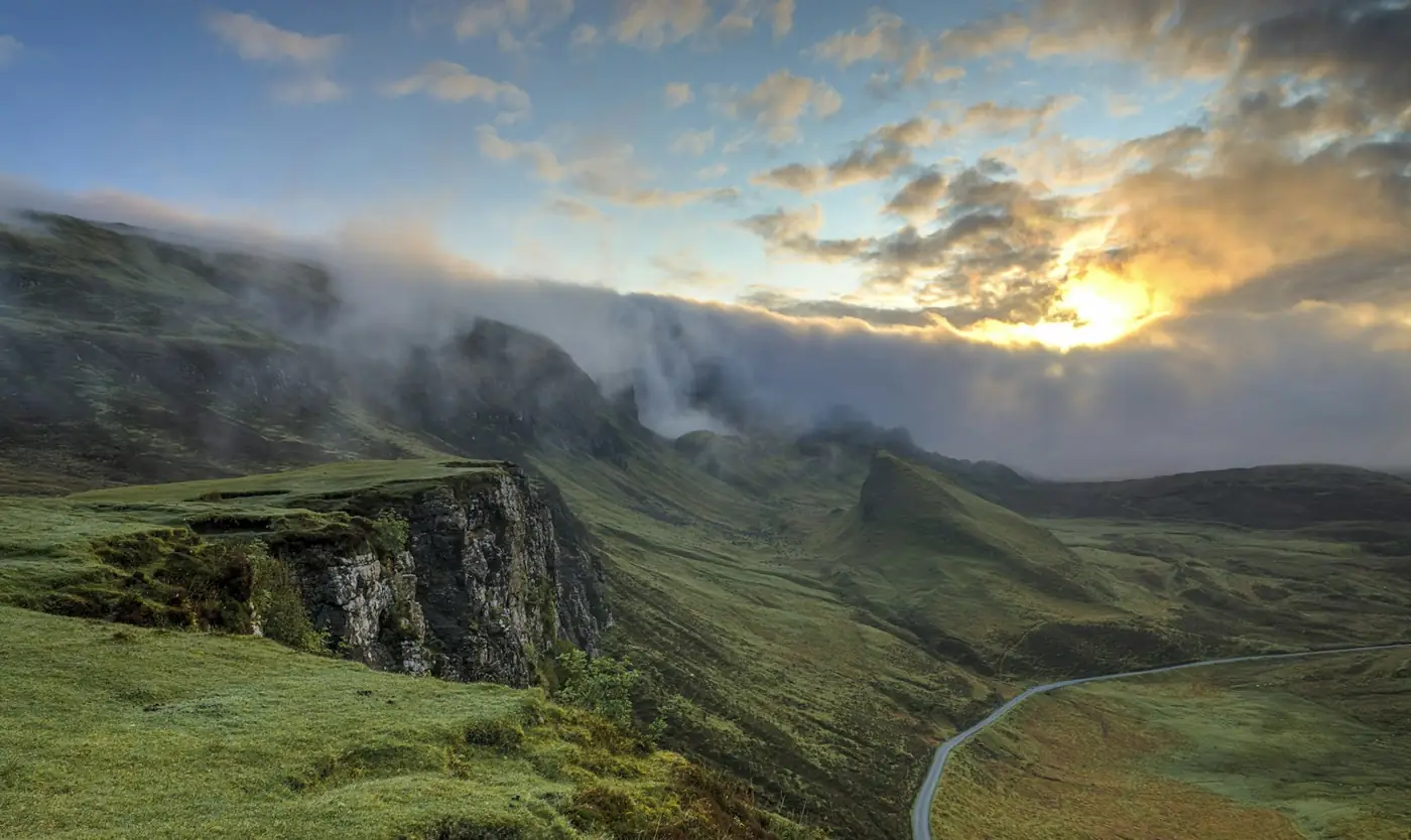Green hills under a low, bright sky with mist in the valley